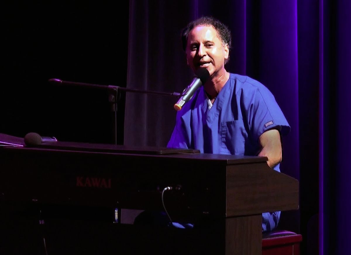 Hospital comedian Dr. Dan at the piano in blue scrubs